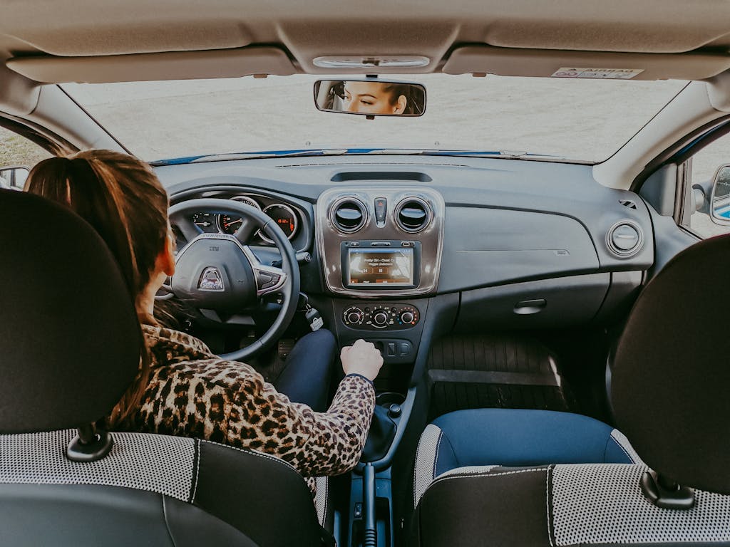 Back view of modern woman in stylish fur coat driving car confidently looking away